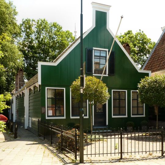 Houten huis door een langgerekte vleugel verbonden met een vierkant tuinhuisje