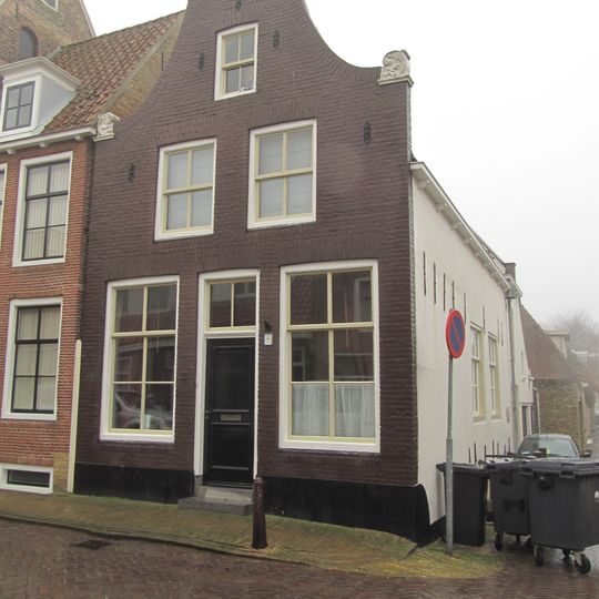 Hoekpand met klokgevel onder diep zadeldak met iets hoger opgetrokken achterhuis