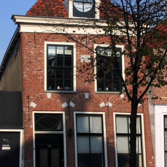 Pand met verdieping, vensternissen en rechte kroonlijst onder zadeldak met dakkapel met ronde fronton