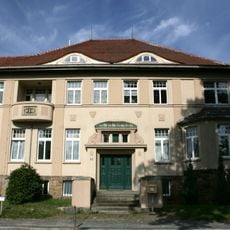 Fabrik Eggert (ehemals); Vereinigte Grobgarnwerke; Verwaltungshaus (Nr. 22) mit seitlichem Anbau, Einfriedung und neben stehender Toreinfahrt, straßenbegleitende Fassade des Fabrikgebäudes und weiteres Fabrikgebäude mit Einfriedung des Grobgarnwer