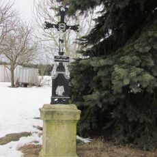 Kříž v západní části Janovic v zahradě domu čp.18