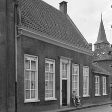 Huis met enkel begane grond en hoog zadeldak tussen puntgevels met vlechtingen en topschoorstenen