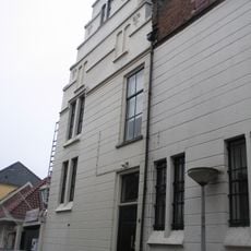 Huis met gepleisterde en gewijzigde trapgevel met sierankers