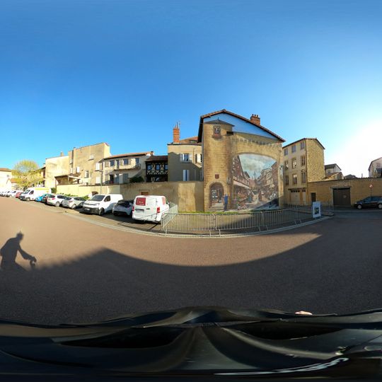 Fresque murale en trompe l'oeil d'une rue médiévale offrant une vision idéalisée de Charlieu. Oeuvre réalisée dans le cadre du 1150ème anniversaire de l'Abbaye de Charlieu, inaugurée le 2025-05-03.