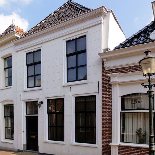 Onderkelderd pand met verdieping en gepleisterde voorgevel onder schilddak