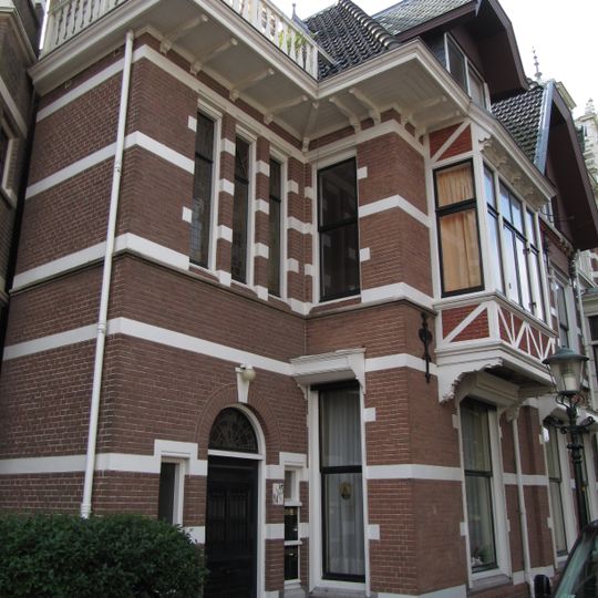 Pand met neo-renaissancegevel. Rechts een afgeknotte puntgevel met houten voorschot. Leeuwenmasker-sluitstenen, vakwerk, vlechtwerk en sierankers