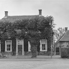 Boerderij op T-vormige plattegrond, waarvan het woonhuis een rieten schilddak draagt en vensters met zesruitsschuiframen bezit. Rechts een zomerhuis, 18e eeuw, onder wolfdak met riet en pannen gedekt