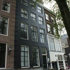 Huis met gevel onder latere rechte lijst waarop een verhoging