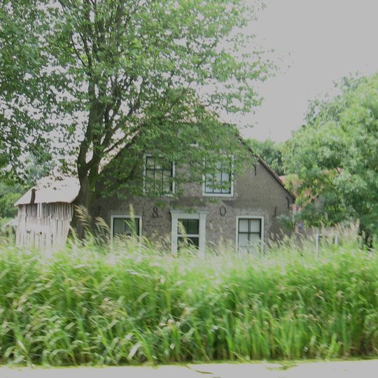 Boerderij onder rieten wolfdak. In de voorgevel van het woongedeelte jaartalankers. Rechts onderkelder. Hooiluik onder opgewipt gedeelte van het dak in de linker zijgevel.