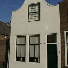 Huis met gepleisterde tuitgevel met stoep