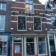 Pand met oorspronkelijk trapgevel met in de verdieping korfbogige ontlastingsbogen, waarin vlechtwerk