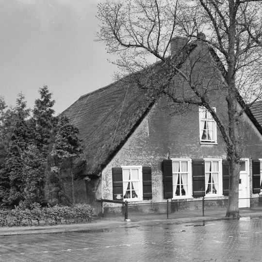 Pand onder met pannen gedekt wolfdak. Vensters met luiken en zes- en negenruitsschuiframen
