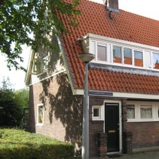 Blok met 8 keukenwoningen, zo genoemd vanwege destijds nieuwe plaatsing van keuken aan de voorzijde, aan de zijkant een houten topgevel, bouwstijl Amsterdamse School.