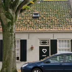 Gepleisterd wevershuisje van begane-grond met pannen zadeldak, dat links aansluit tegen een puntgevel