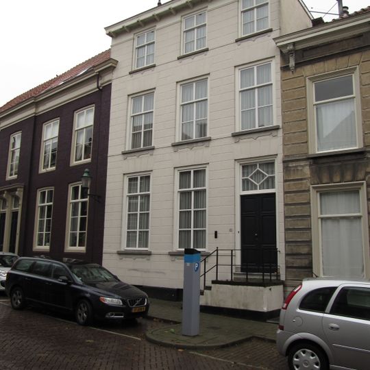 Huis met gebosseerd gepleisterde lijstgevel en trap met bordes voor de ingang