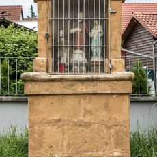 Gemauerter Altarsockel mit Nischenaufsatz; Metallgitter und Verglasung; drei Heiligenfiguren