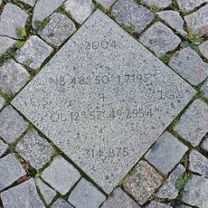 Granit Stein mit Koordinaten und Höhenangabe, die 2004 deutet auf die Neugestaltung des Luitpoldplatz hin