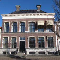 Drie traveeën breed pand met eenvoudige gevel met bloklijst aan kroonlijst, samen met nr. 49 onder U-vormig zadeldak