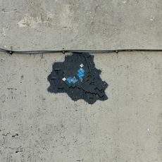 Extraterrestre gris, yeux bleu, qui fait de la tirolienne sur le cable electrique qui passe sur le mur de l'immeuble