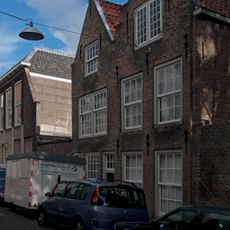 Pand met puntgeveltje met vlechtingen. Met pand rechts daarvan.