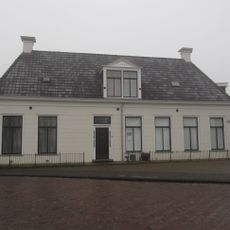 Laag gerekt hoekpand onder schilddak met hoekschoorstenen en dakkapel