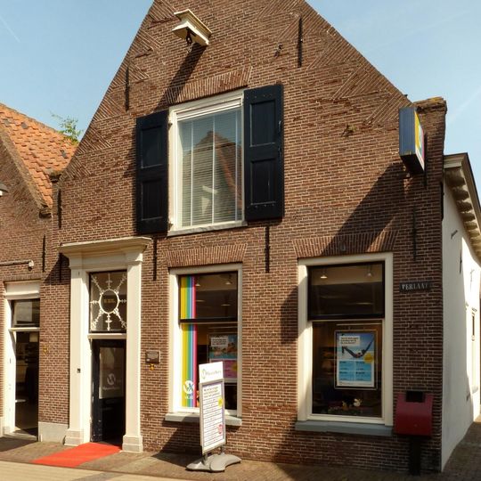 Hoekpand onder zadeldak met aan de voorzijde een puntgevel met vlechtingen en tuitbekroning met geprofileerde, gebogen afdekking