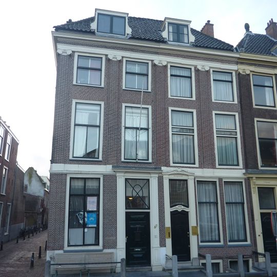 Pand onder een dak met het nr 55. Ionische pilasterstelling over beide verdiepingen. Deuren en vensters gewijzigd. Eenvoudige deuromlijsting. Hardstenen stoep en palen.