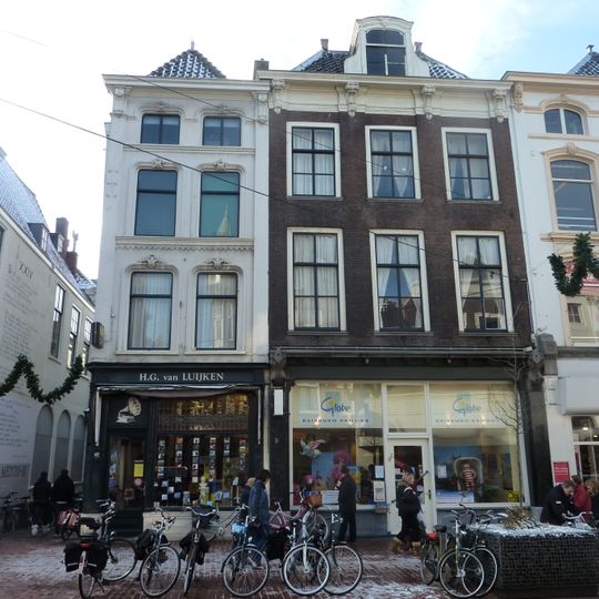 Pand met bakstenen gevel bovendeel met pilasters, rechte kroonlijst met consoles en groot dakvenster