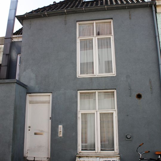 Perceelsgedeelte met gepleisterde rechte gevel. Gootlijst op klossen. Schilddak. Kelderluik