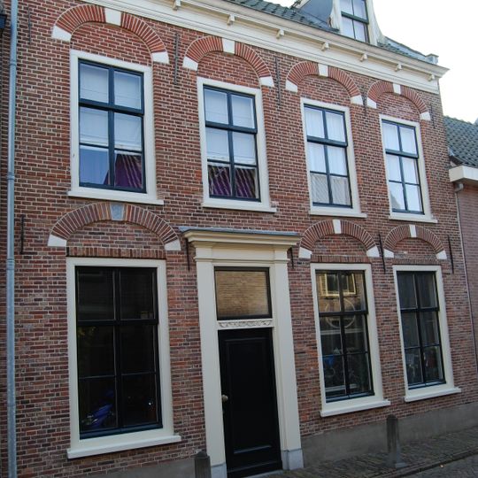 Huis met in de gevel geblokte ontlastingsbogen en in de verdieping schuiframen