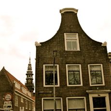 Pand met klokgevel met voluten en houten afdekking, top 1765, ouder huis uit 17e eeuw in raamsteeg aanwezig