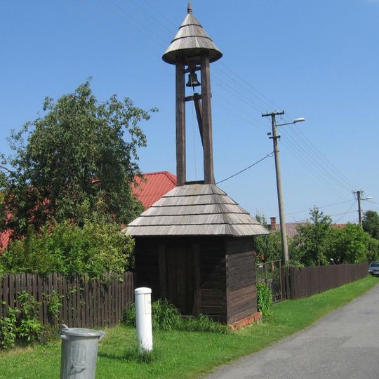 Dřevěná zvonice u silnice uprostřed Lázů