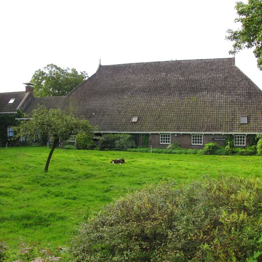 Kop-hals-rompboerderij met onderkelderd woonhuis met zesruitsvensters en met bedrijfsruimte aan de zijde van de stal