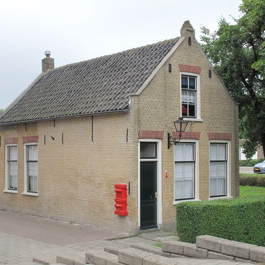 In oorsprong ten behoeve van de naastgelegen korenmolen 'de Hoop' gebouwde molenaarswoning, bestaande uit een verdiepingloos pand onder met blauwe pannen gedekt zadeldak tussen tuitgevels.
