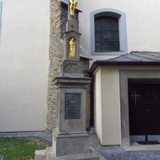 Tmavý kříž u kostela Nanebevzetí Panny Marie v Rouchovanech