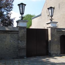 Muur met ezelsrugafdekking en inrijpoort