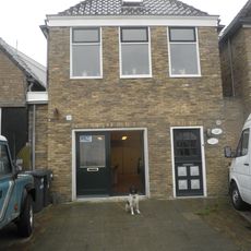 Eenvoudig pandje met topgevel van gele steen met beitelingen