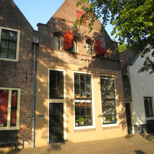 Pakhuis onder zadeldak met gepleisterde tuitgevel. Geprofileerde natuurstenen dekstukken op schouders en top. Getoogde zolder- en vlieringluiken; hijsankers. Begane grond gewijzigd