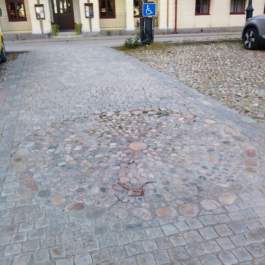 Vid den här platsen så har det funnits en skampåle. Idag så består bara platsen för pålen i mitten av en cirkeln av stenar. At this location there used to be a pillory. All that remains today is the location of the pole itself within a circle of stones.