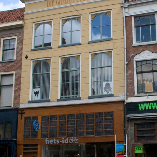 Pand met gepleisterde gevel, forse kroonlijst, halfronde beëindigde ramen op de verdiepingen en jongere onderpui