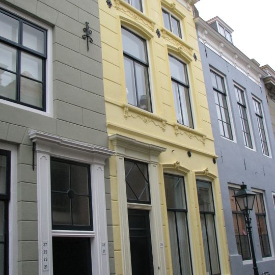 Huis met laatste helft 19e-eeuwse gepleisterde lijstgevel met consoles. Eenvoudige voordeuromlijsting. Stoeptreden