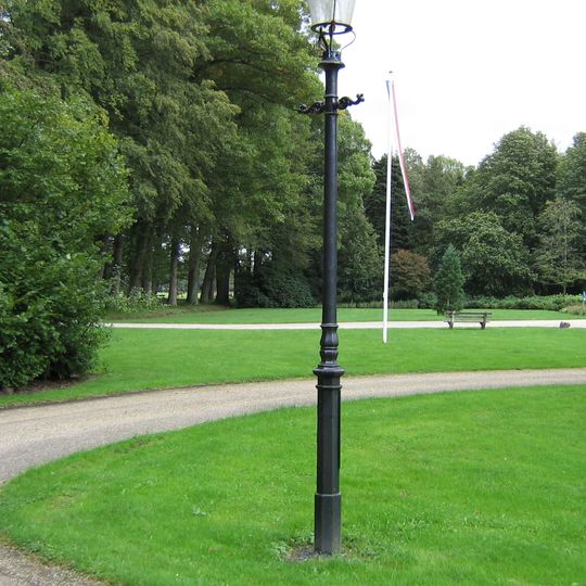 Drie gietijzeren lantaarnpalen gelegen aan pad dat de villa verbindt met het badgebouw