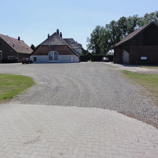 Gepleisterde boerderij op T-vormige plattegrond. Lage bovenverdieping, met riet gedekt schilddak