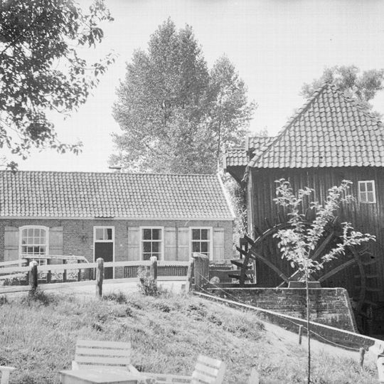 Eenvoudig verdiepingloos pand gedekt door twee dwarse zadeldaken tussen houten topgevels