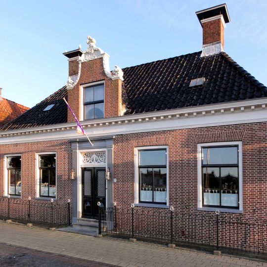 Landelijk breed woonhuis met verdieping onder schilddak met hoekschoorstenen waarop borden