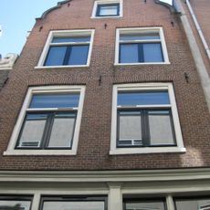 Pand, later met een verdieping verhoogd huis, waarvan de gevel wordt afgesloten door een uit- en ingezwenkte top onderrollagen