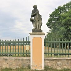 Alegorická socha Duben v ohradě zámecké zahrady ve Veltrusech
