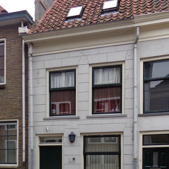 Pand met gecementeerde gevel onder hoog schilddak dat links eindigt in topgevel