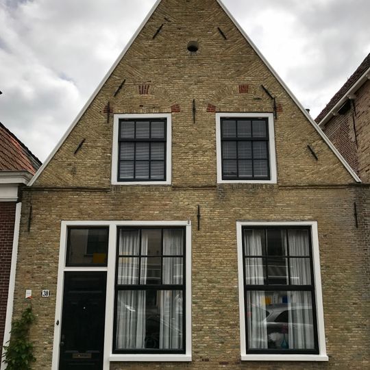 Pand onder zadeldak tegen rechts onderkelderde topgevel met bogen boven de vensters en waterlijst