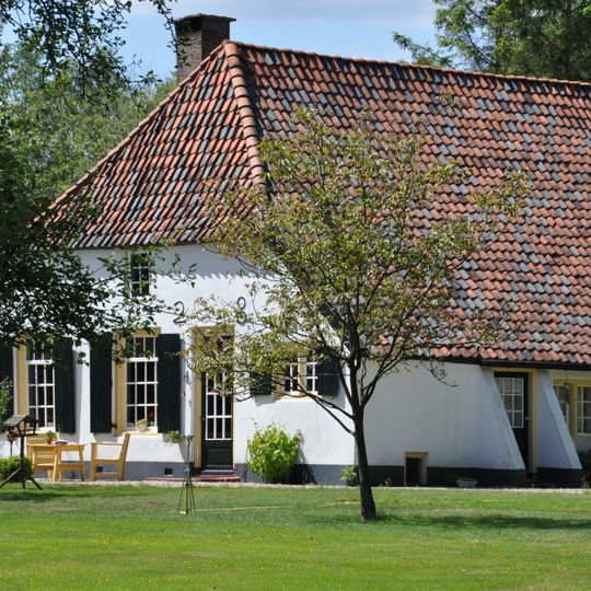 Gepleisterde boerderij onder met pannen gedekt wolfdak
